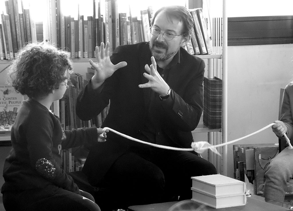 Photo de Tomarel racontant son conte aux enfants dans la bibliothèque d'une école